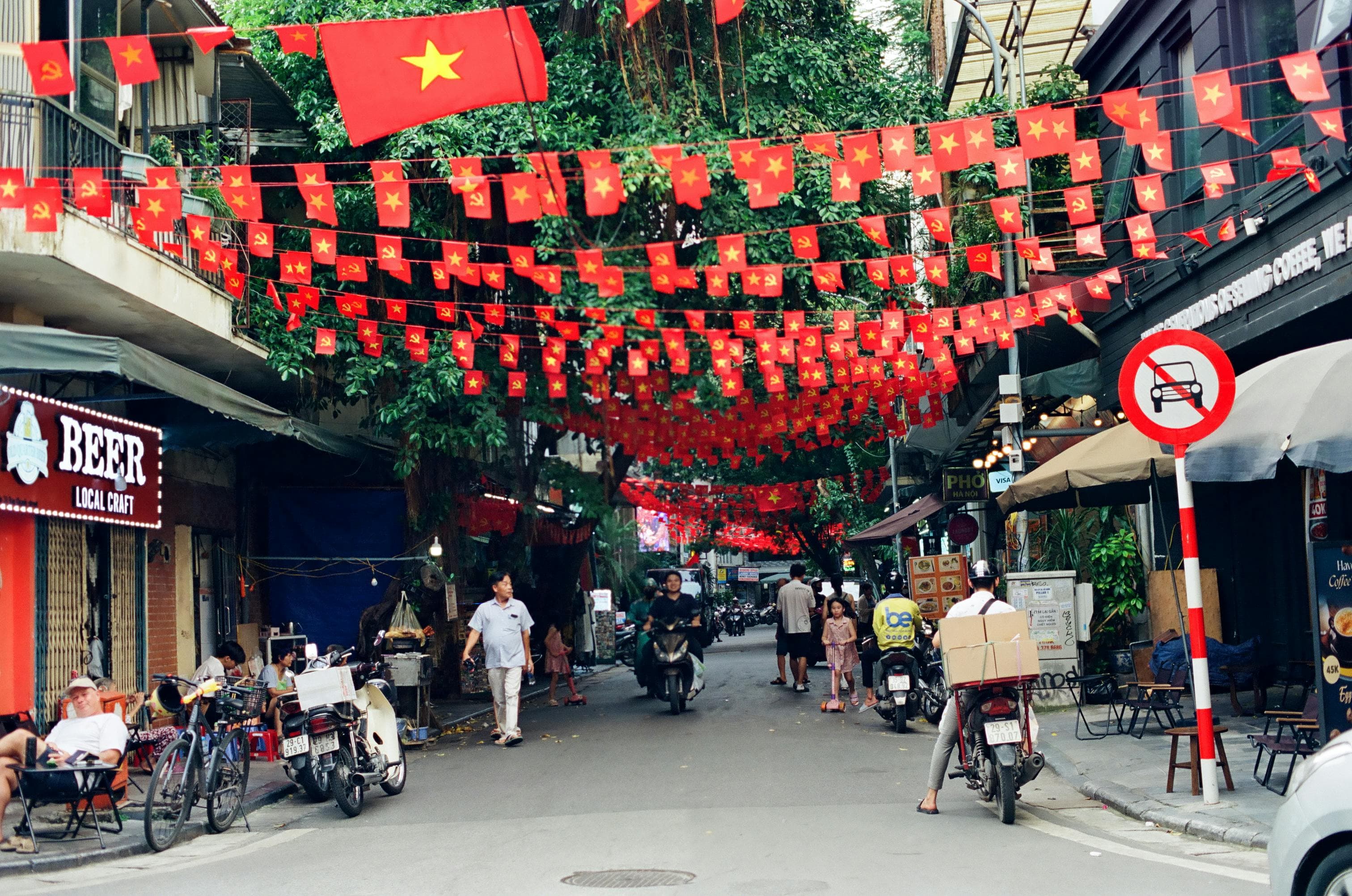Hanoi Old Quarter street with Vietnam flags and traditional daily life