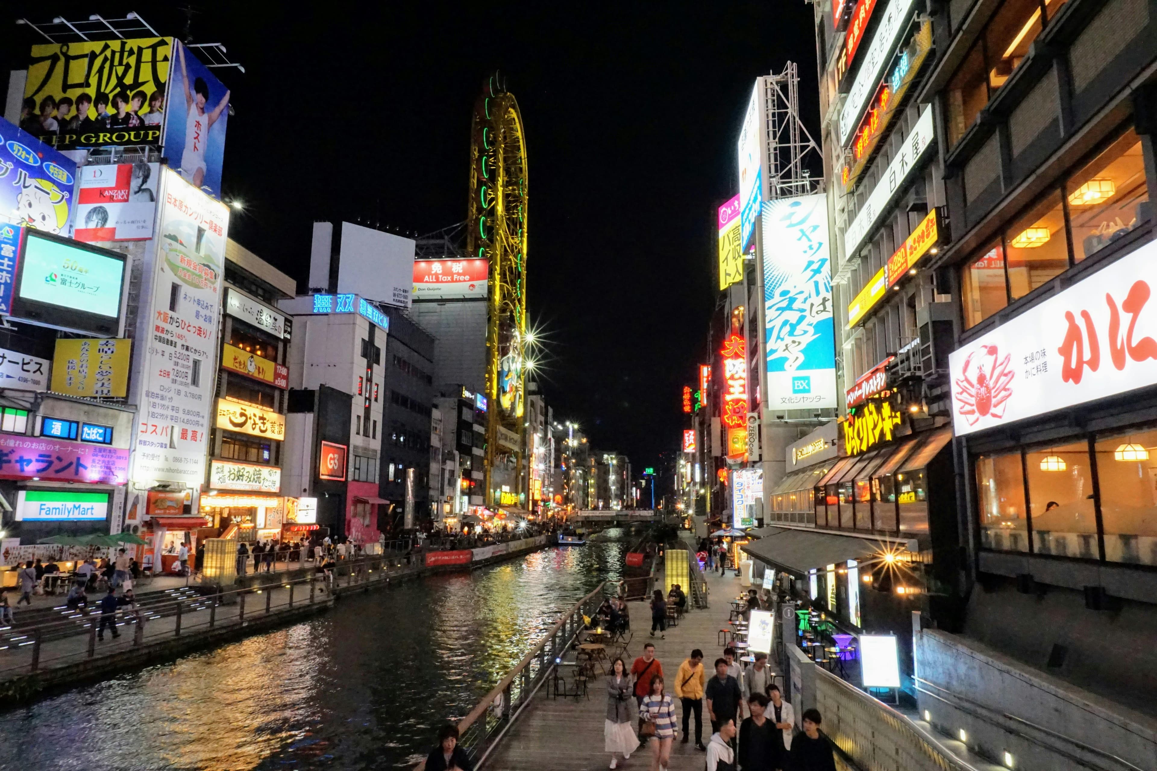 Dotonbori canal at night with neon signs and Don Quijote ferris wheel reflecting on the water