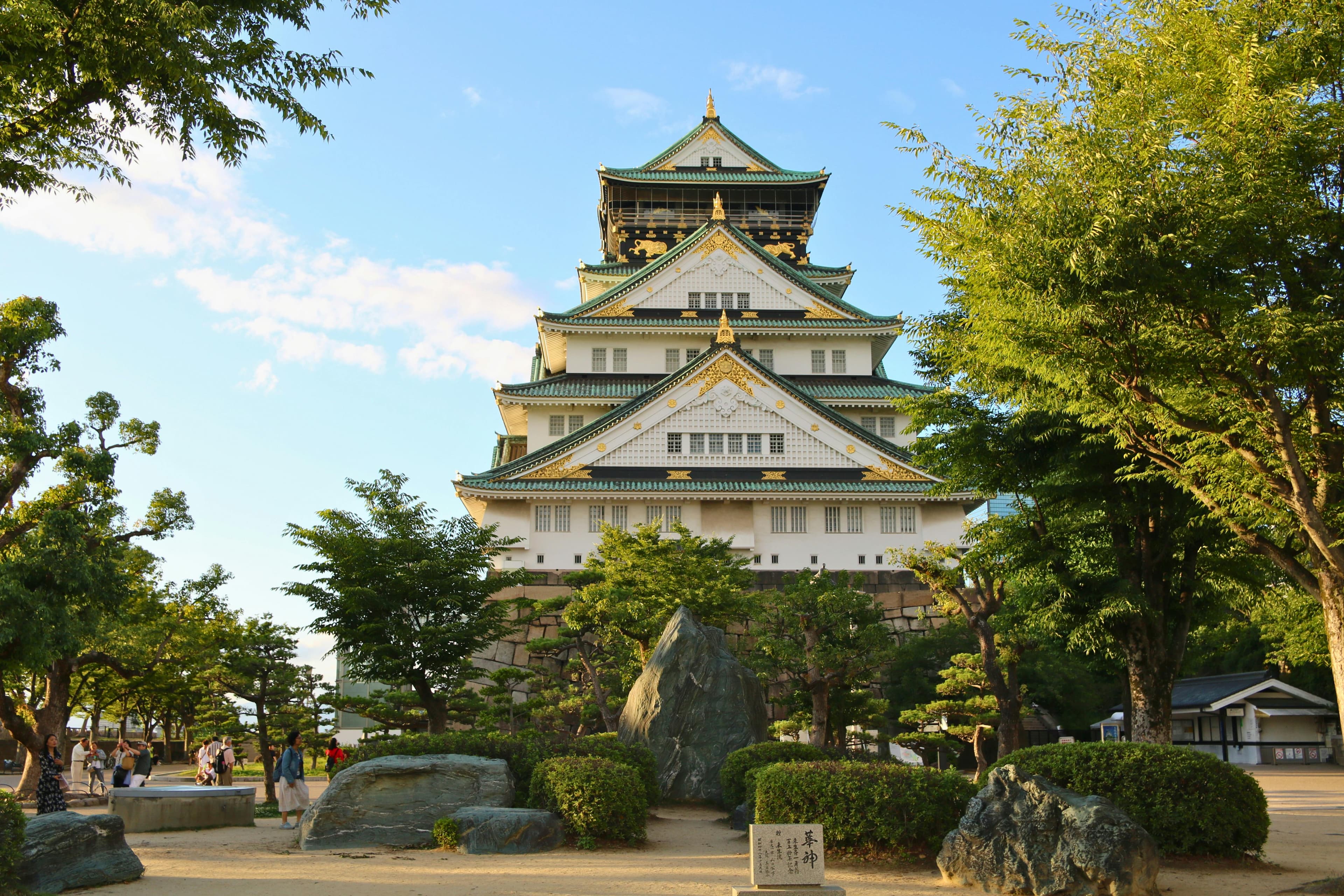 Osaka Castle main tower with cherry blossoms in spring 2026 contrasting with Kyoto traditional architecture