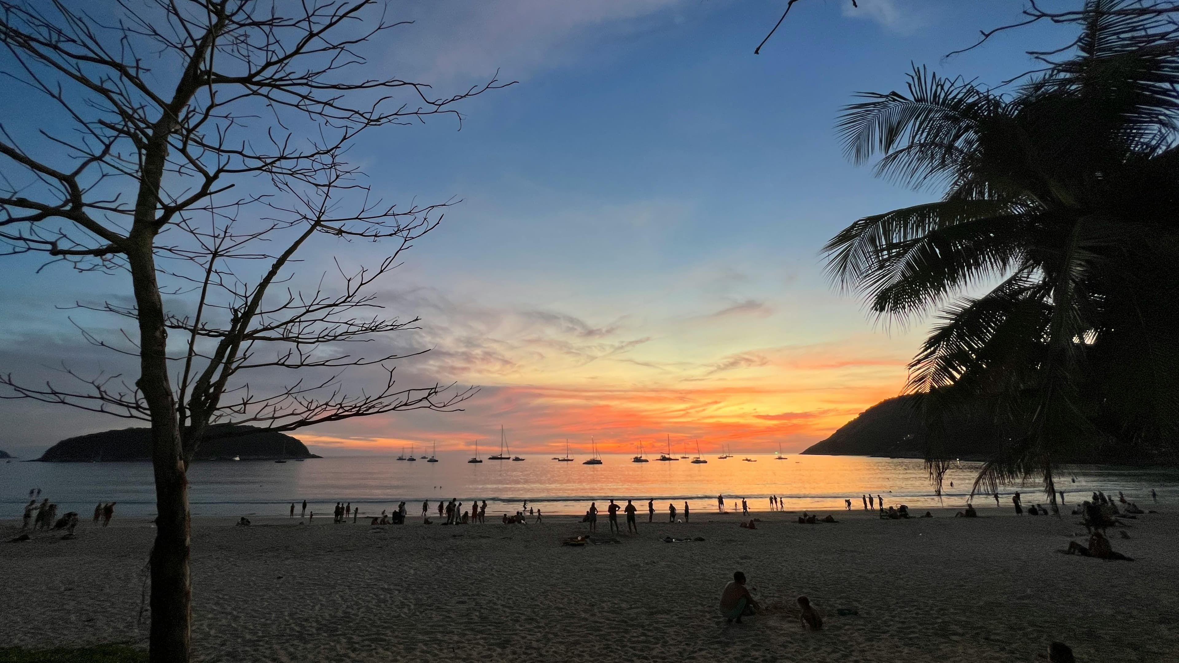 Golden sunset over Patong Beach with silhouettes of people enjoying the famous nightlife