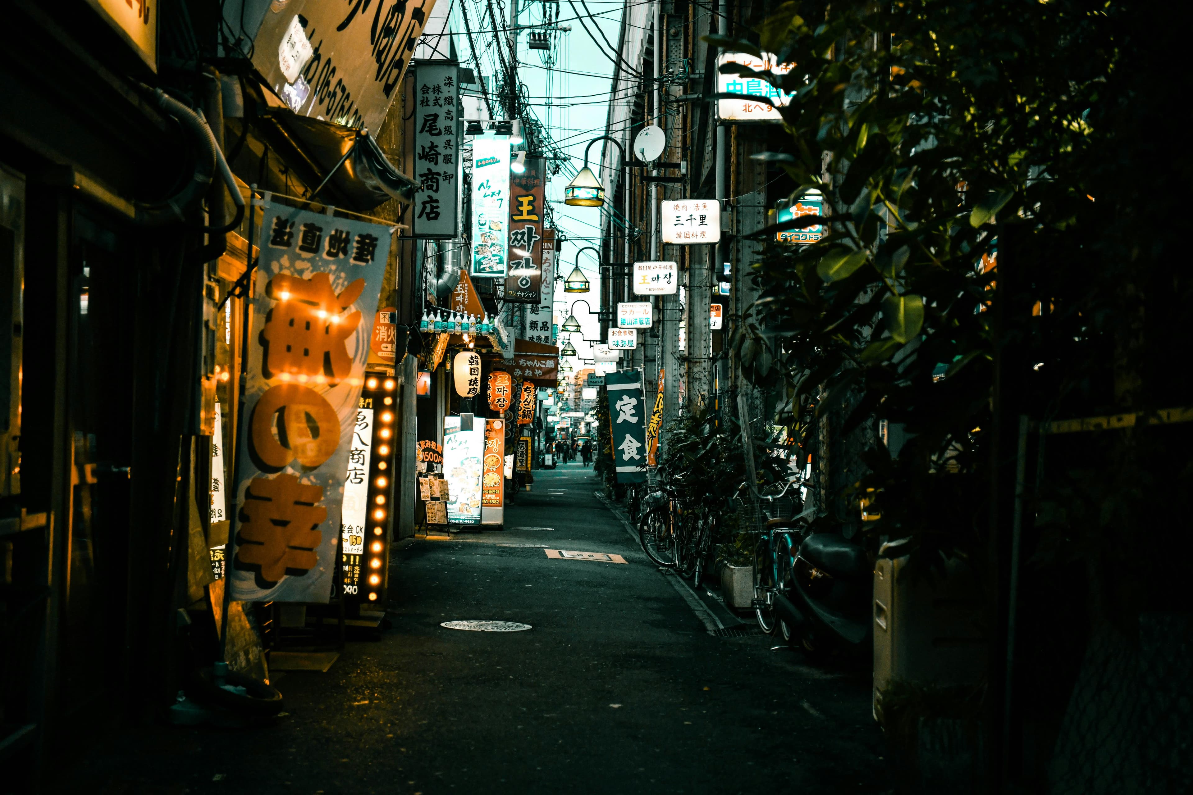 Narrow Tokyo alley at night with orange lanterns and Japanese bar signs in Shinjuku Golden Gai atmosphere