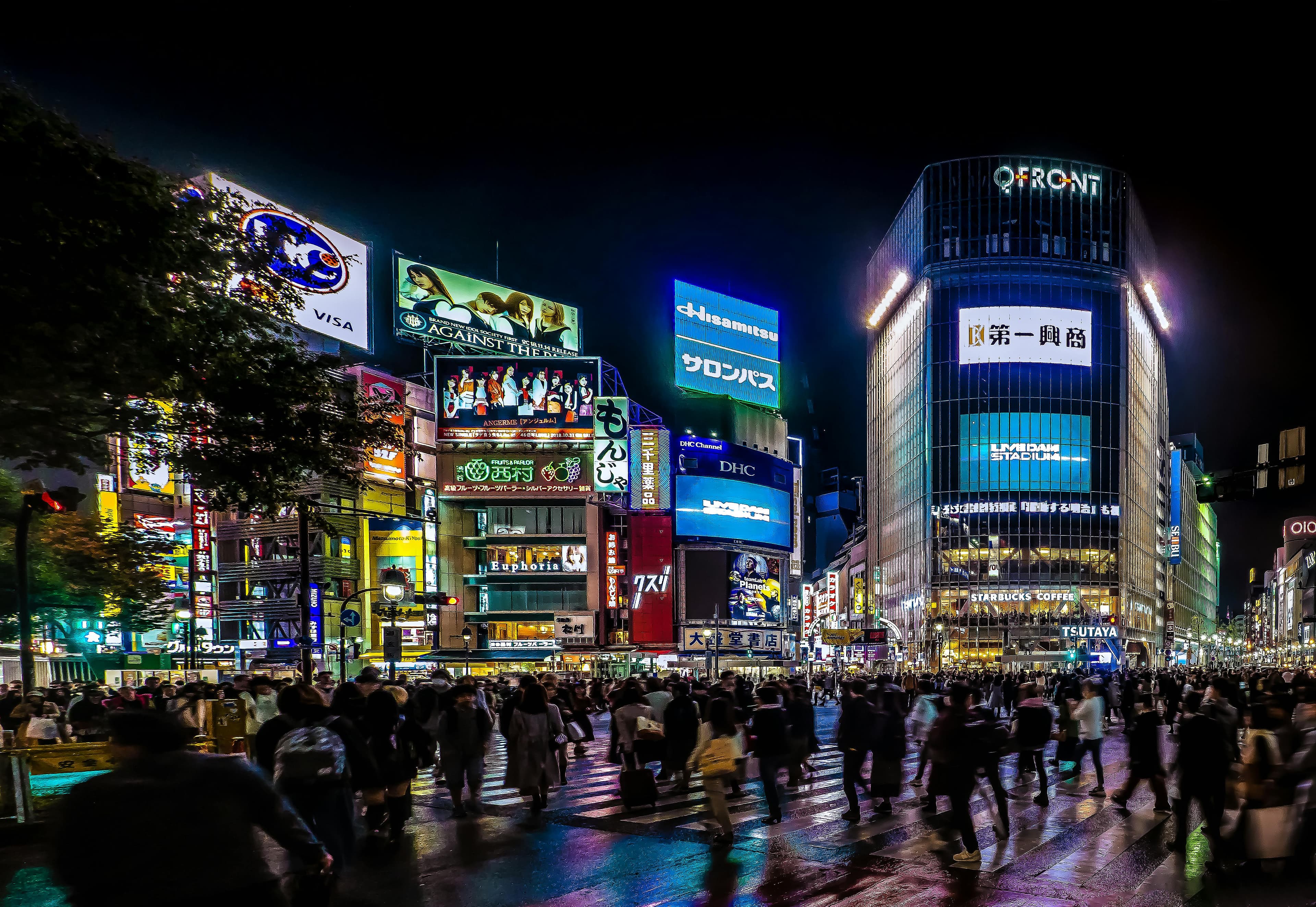 Shibuya Crossing at night with neon billboards and crowds crossing the famous intersection in Tokyo