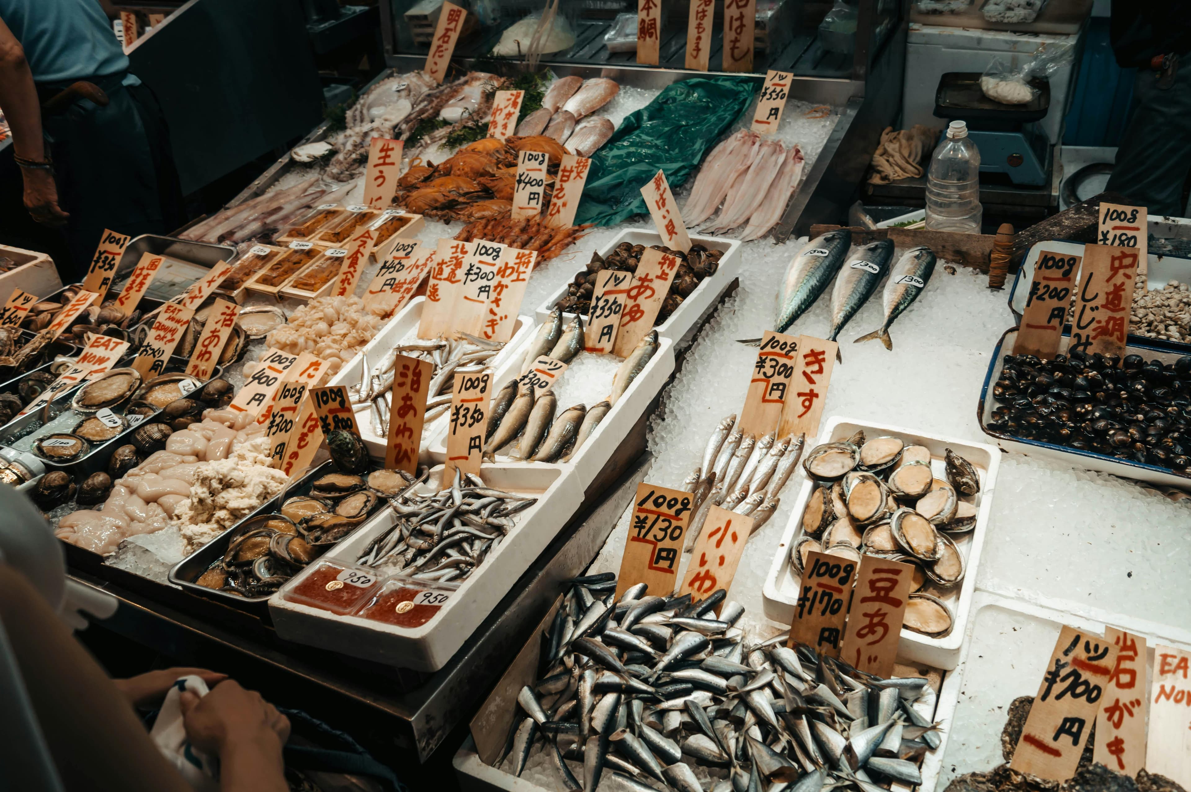 Fresh seafood and fish on ice at Tsukiji Outer Market with handwritten yen price signs in Tokyo