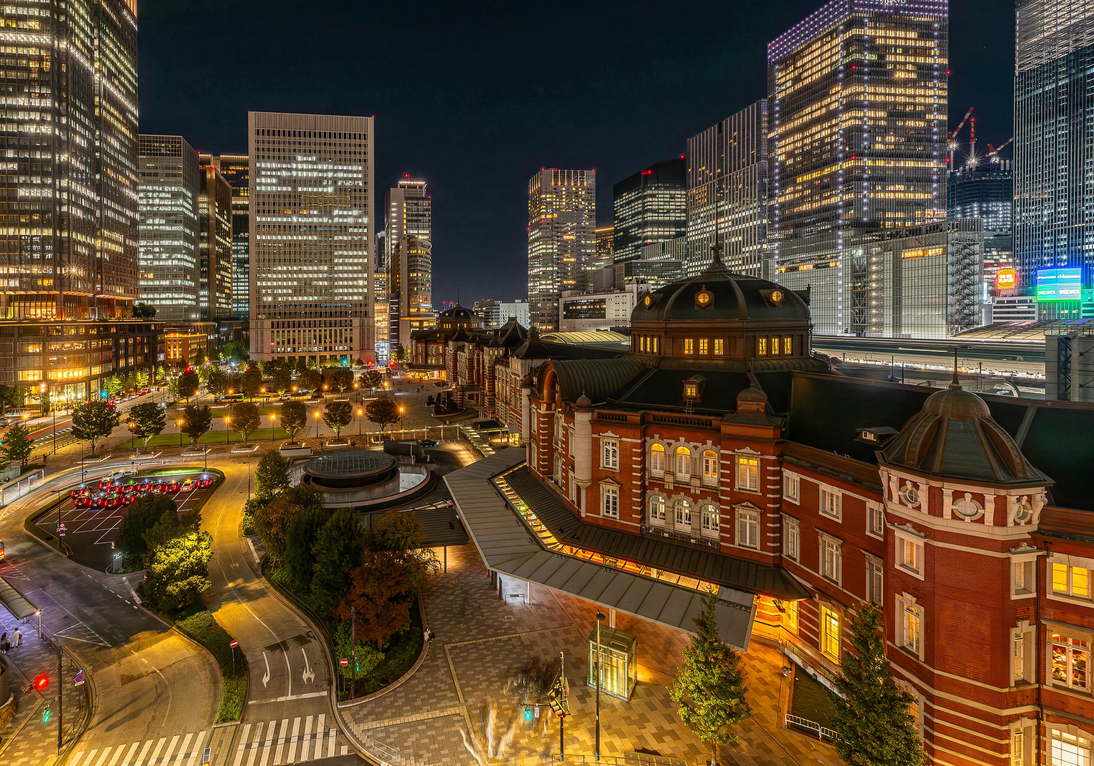 Tokyo Station red brick Marunouchi building at night with illuminated business district skyscrapers